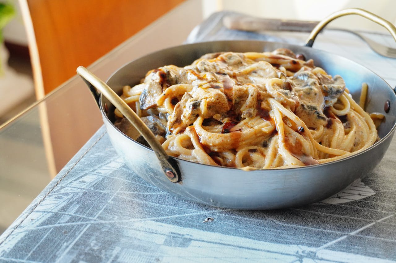 Close-up of creamy pasta in a pan, capturing rich textures and flavors.