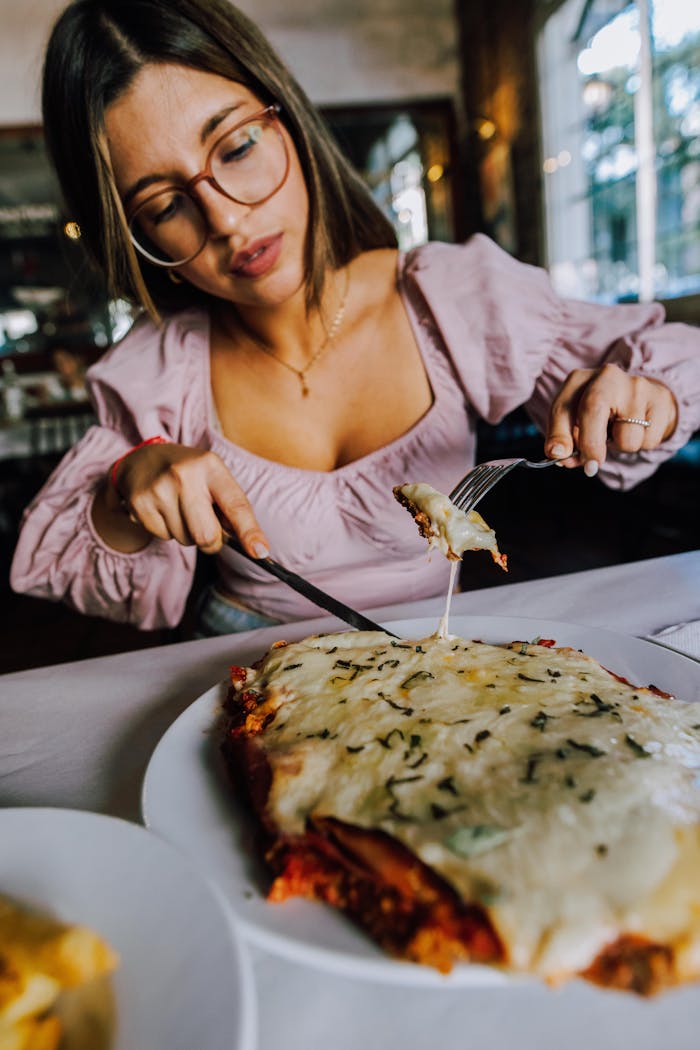 A woman relishing a cheese-laden dish in a cozy Buenos Aires restaurant.