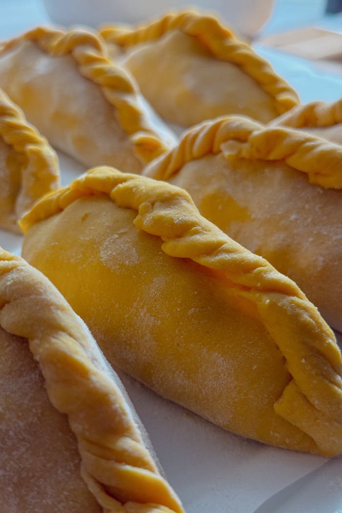 Delicious homemade empanadas with flaky crust on a table ready to bake.